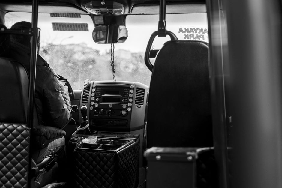 Een buschauffeur rijdt door de stad, omringd door passagiers en druk verkeer, symboliserend de verantwoordelijkheden van het chauffeurswerk.